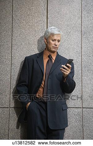 Businessman looking down at cell phone View Large Photo Image Stock Image - Businessman looking down at cell phone. Fotosearch