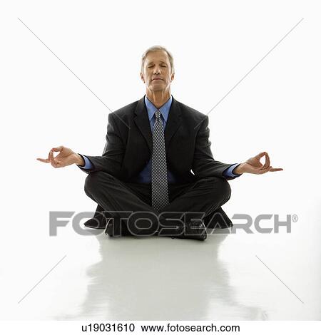 Stock Image - Businessman meditating in yoga lotus pose on floor. Fotosearch