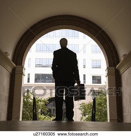 Stock Photography - Businessman silhouette standing in archway holding briefcase. Fotosearch