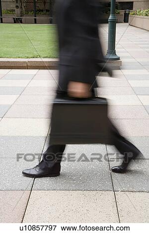 Businessman walking outdoors with briefcase View Large Photo Image Stock Photo - Businessman walking outdoors with briefcase. Fotosearch