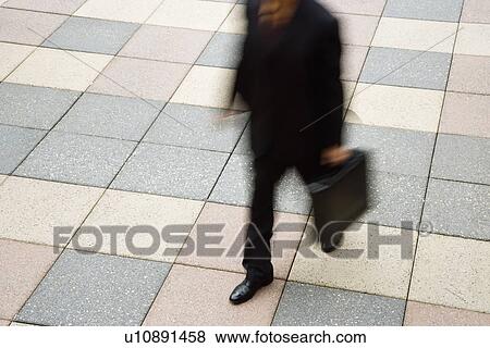 Stock Photo - Businessman walking outdoors with briefcase. Fotosearch