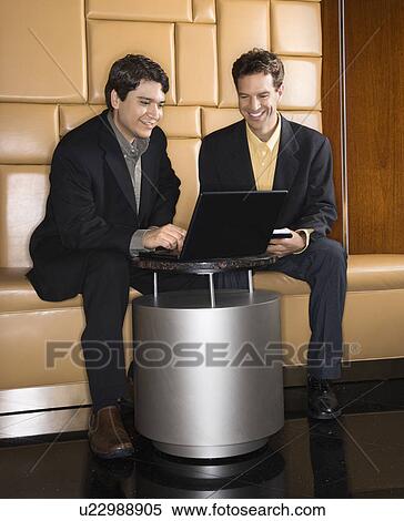 Stock Photography - Businessmen talking and viewing laptop computer.. Fotosearch