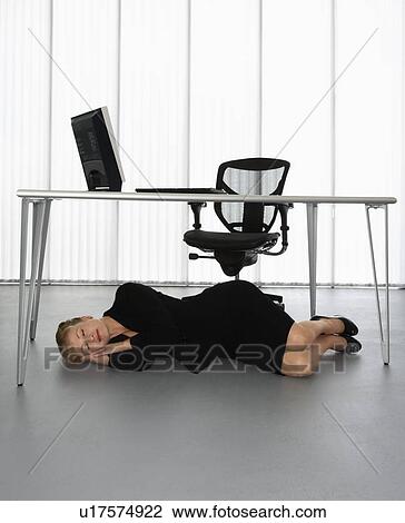 Businesswoman Sleeping On Floor Under Computer Desk Stock Image