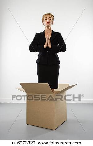Stock Photo - Businesswoman standing inside cardboard box meditating with eyes closed. Fotosearch