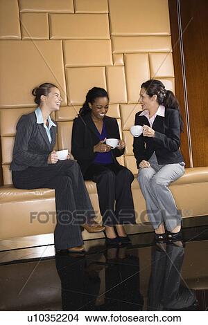 Businesswomen drinking coffee and conversing. View Large Photo Image Picture - Businesswomen drinking coffee and conversing.. Fotosearch