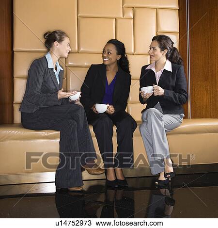 Stock Image - Businesswomen drinking coffee and talking. Fotosearch