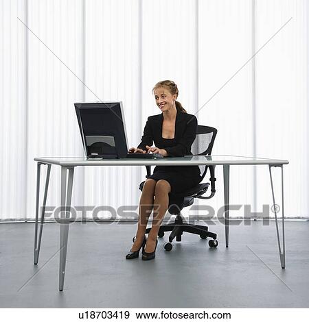 Caucasian businesswoman sitting at desk with computer working. View Large Photo Image Stock Photo - Caucasian businesswoman sitting at desk with computer working.. Fotosearch