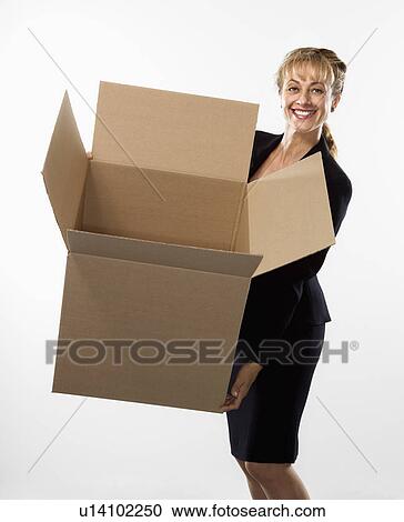 Stock Image - Caucasian businesswoman standing holding empty cardboard box smiling at viewer.. Fotosearch
