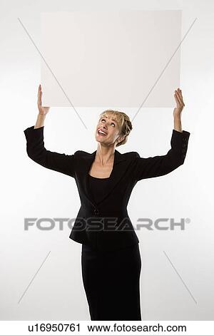 Stock Image - Caucasian businesswoman standing holding blank sign above head.. Fotosearch