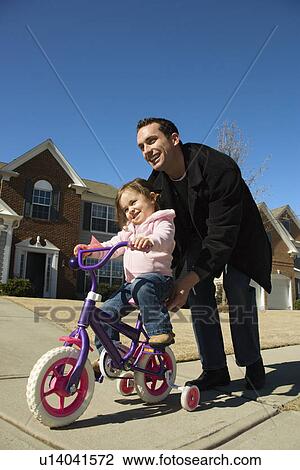 Caucasian father helping daughter ride bicycle. View Large Photo Image Stock Image - Caucasian father helping daughter ride bicycle.. Fotosearch
