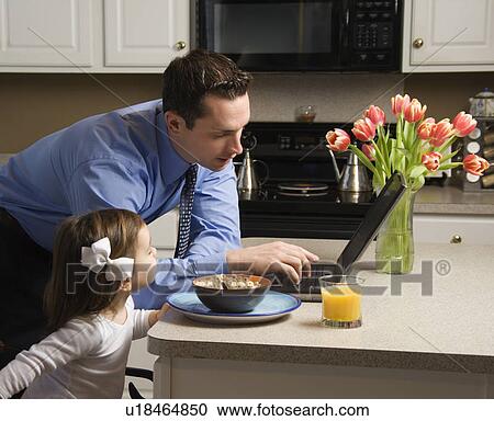 Caucasian father in suit using laptop computer with daughter eating breakfast in kitchen. View Large Photo Image Stock Image - Caucasian father in suit using laptop computer with daughter eating breakfast in kitchen.. Fotosearch