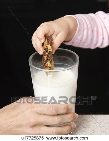 Caucasian girl dipping chocolate chip cookie into glass of milk. View Large Photo Image Stock Photography - Caucasian girl dipping chocolate chip cookie into glass of milk.. Fotosearch