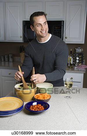 Stock Photo - Caucasian man making salad on kitchen counter.. Fotosearch
