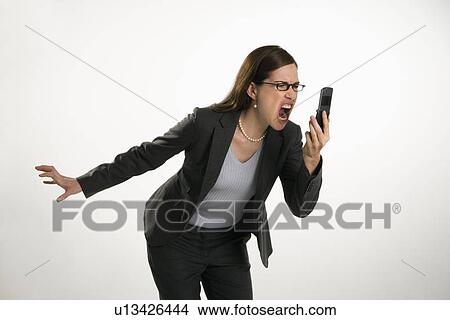 Picture - Caucasian mid adult professional business woman yelling into cell phone in anger.. Fotosearch