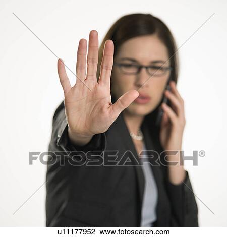 Stock Image - Caucasian mid adult professional business woman talking on cell phone holding hand out to stop viewer. viewer. . Fotosearch