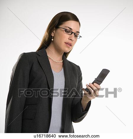 Stock Image - Caucasian mid adult professional business woman text messaging on cell phone.. Fotosearch