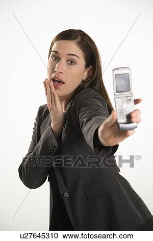 Stock Image - Caucasian mid adult professional business woman taking picture of self with camera phone with hand on chin.. Fotosearch