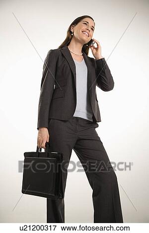 Stock Photo - Caucasian mid adult professional business woman holding briefcase, talking on cell phone and smiling.. Fotosearch