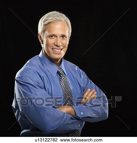 Stock Image - Caucasian middle aged businessman smiling at viewer with arms crossed.. Fotosearch