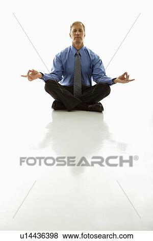 Stock Photo - Caucasian middle aged businessman meditating in yoga lotus pose on floor.. Fotosearch
