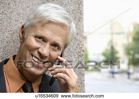Caucasian middle aged businessman talking on cell phone smiling at viewer. View Large Photo Image Stock Photo - Caucasian middle aged businessman talking on cell phone smiling at viewer.. Fotosearch