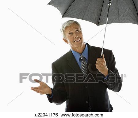 Stock Photograph - Caucasian middle aged businessman holding umbrella and gesturing.. Fotosearch
