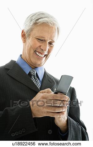 Stock Photograph - Caucasian middle aged man smiling and text messaging on cell phone.. Fotosearch