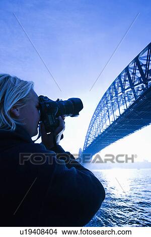 Picture - Caucasian teenage male photographing Sydney Harbour Bridge at dusk with view of Sydney Harbour, Australia.. Fotosearch