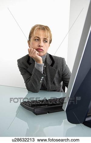 Stock Image - Caucasian woman looking bored at computer.. Fotosearch
