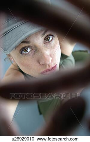 Stock Image - Caucasian woman looking up at viewer through hands.. Fotosearch