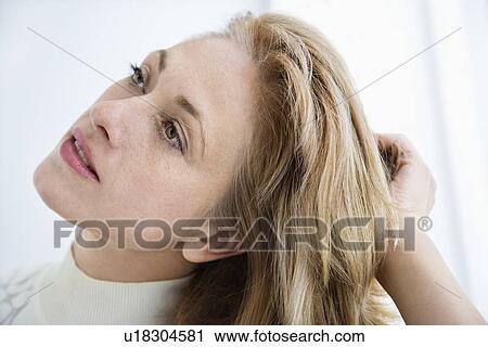 Stock Image - Caucasian woman with hand to long hair looking away.. Fotosearch