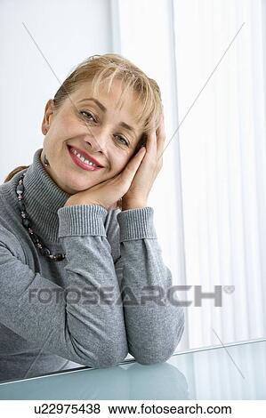 Caucasian woman with head resting on hand smiling at viewer. View Large Photo Image Stock Photo - Caucasian woman with head resting on hand smiling at viewer.. Fotosearch