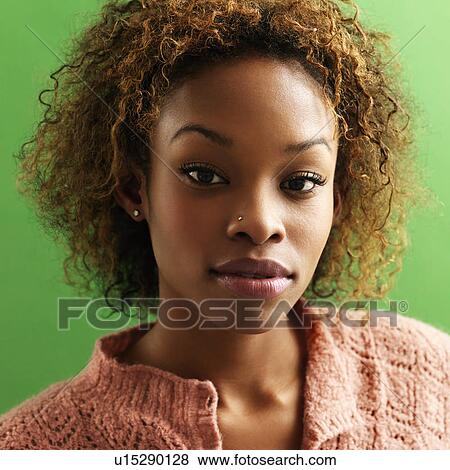 Stock Photo - Close up portrait of pretty young woman against green background.. Fotosearch