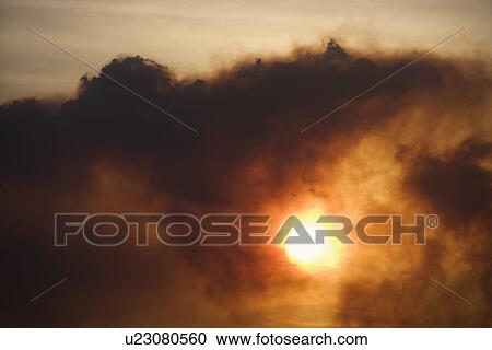 Stock Image - Dark clouds at sunset. Fotosearch