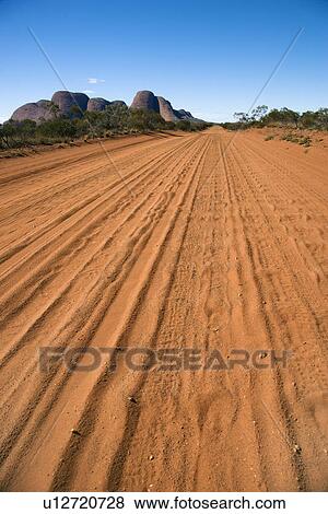 Dirt road with tire tracks in Uluru Kata Tjuta National Park, Australia with Mount Olga in the distance. View Large Photo Image Stock Photo - Dirt road with tire tracks in Uluru Kata Tjuta National Park, Australia with Mount Olga in the distance.. Fotosearch