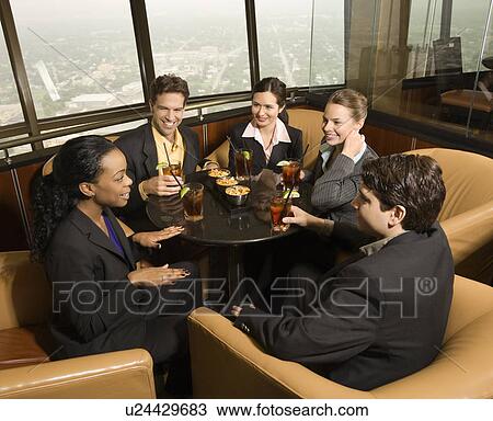 Stock Image - Ethnically diverse businesspeople sitting at table in restaurant talking.. Fotosearch