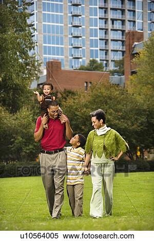 Family of four people walking in park smiling. View Large Photo Image Stock Photography - Family of four people walking in park smiling.. Fotosearch