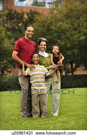 Family of four standing in park smiing. View Large Photo Image Stock Image - Family of four standing in park smiing.. Fotosearch