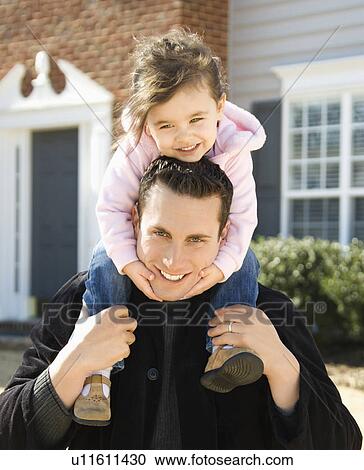 Stock Image - Father carrying daughter on shoulders. Fotosearch
