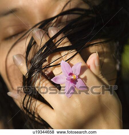 Stock Photo - Female holding flower up to her face. Fotosearch