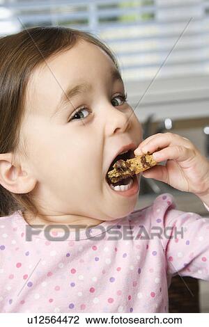 Stock Image - Girl eating chocolate chip cookie. Fotosearch