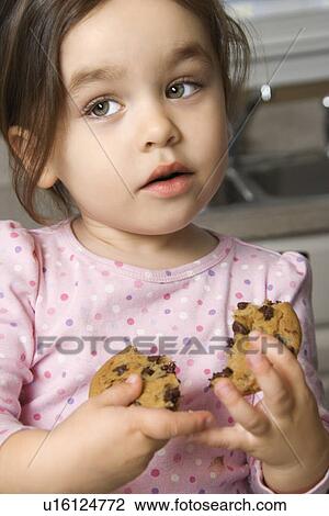 Stock Image - Girl eating chocolate chip cookie. Fotosearch