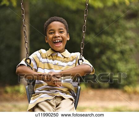 Happy smiling boy on swing in park playground View Large Photo Image Stock Image - Happy smiling boy on swing in park playground. Fotosearch