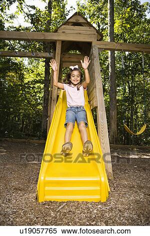 Hispanic girl sliding down outdoor slide with arms raised above head. View Large Photo Image Stock Photography - Hispanic girl sliding down outdoor slide with arms raised above head.. Fotosearch