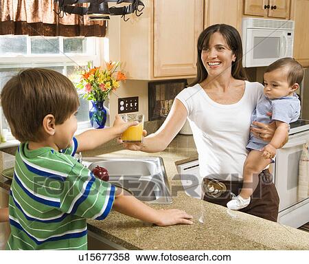 Stock Photo - Hispanic mother and children in kitchen with juice. . Fotosearch