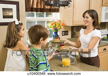 Stock Photo - Hispanic mother giving healthy breakfast to young children in home kitchen.. Fotosearch
