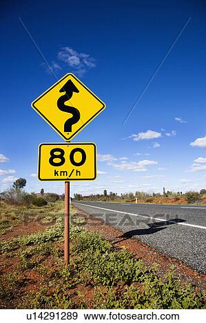 Stock Photo - Kilometer per hour speed limit and curve ahead road signs in rural Australia.. Fotosearch