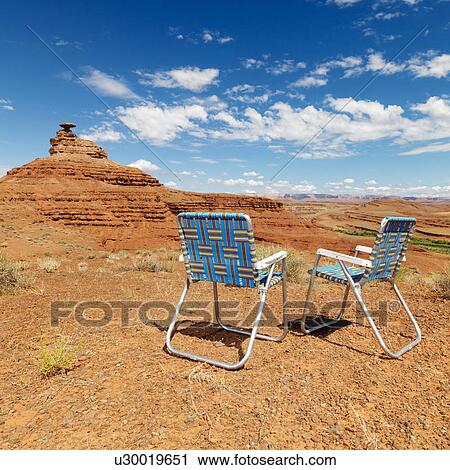 Stock Image - Lawn chairs in scenic desert landscape with mesa land formation.. Fotosearch