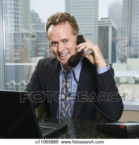 Male on phone in office with skyline in background View Large Photo Image Stock Photo - Male on phone in office with skyline in background. Fotosearch