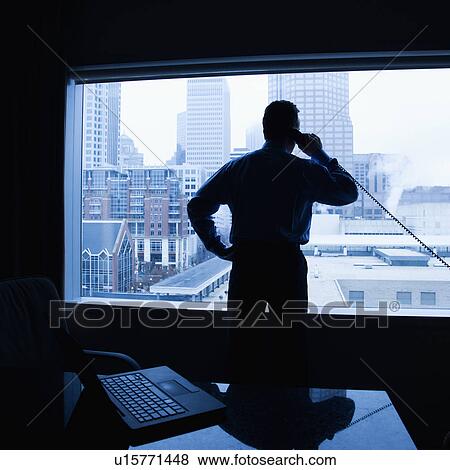 Stock Photo - Male on phone in office with skyline in background. Fotosearch